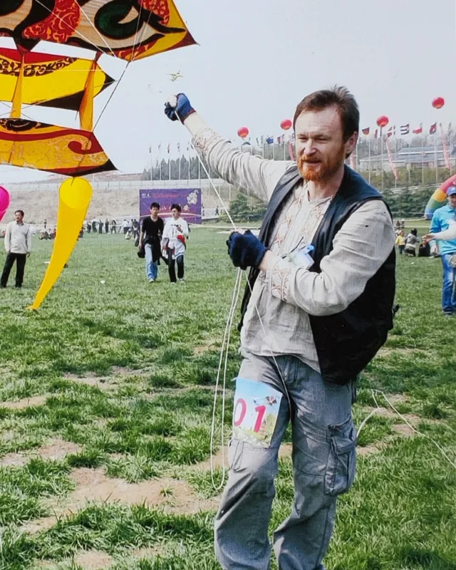 Alex en un campo de festival sujetando la línea de su gato-tigre amarillo