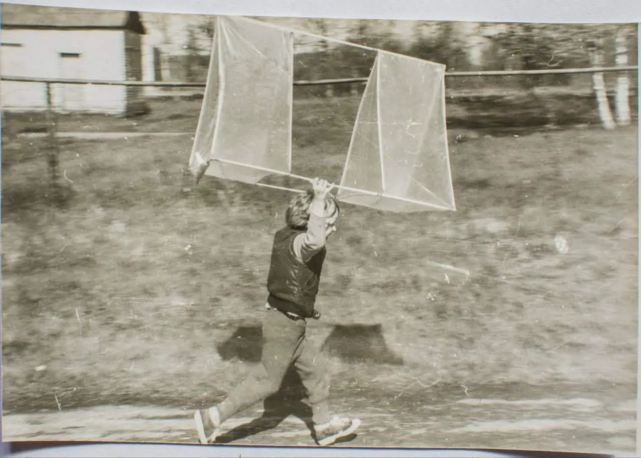 Un niño corriendo con una cometa de caja casera, foto en blanco y negro
